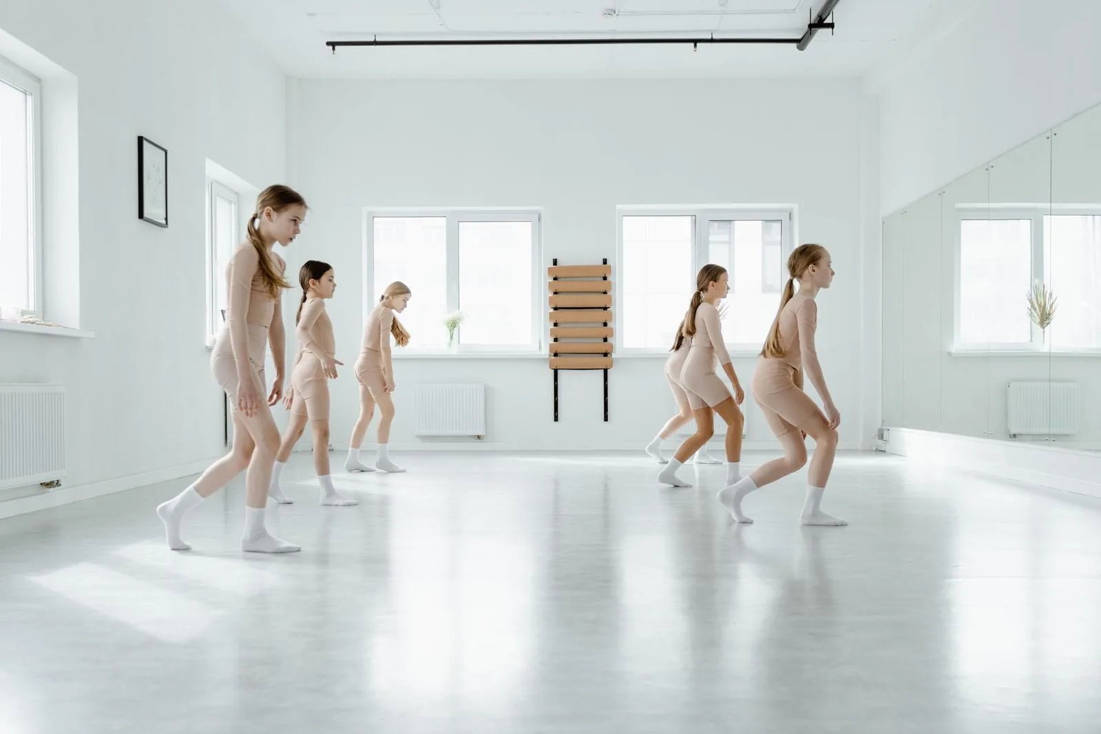 Children in a dance class moving across a bright studio